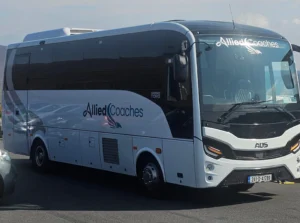 White tour bus with Allied Coaches branding visible on the side and front, parked in a lot.