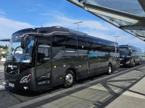 Black coach bus parked at a bus depot, Allied Coaches branding visible on the side against a blue sky background